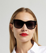 A woman with straight blonde hair wears Carolina Herrera HER0394/G/S Women Sunglasses, red lipstick, and a white collared shirt against a plain light background.