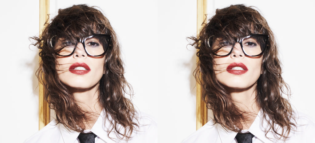 A woman with wavy brown hair, bright red lipstick, and large black glasses, wearing a white shirt and black tie, poses in front of a white wall; the same image is duplicated side by side.