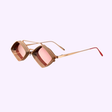 The Vysen Jaxs J-6 Unisex Sunglasses by Vysen Sunglasses feature geometric gold frames, red-tinted lenses, and textured detailing along the rims and arms. Handcrafted in Italy with the signature Jaxs J-6 design, these sunglasses are showcased on a light purple background.