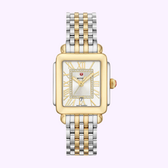 The Michele MWW06G000013 Deco Madison by Michele Watches features a diamond-accented white dial with Roman numerals, a gold-tone square case, and a two-tone stainless steel women's bracelet, displayed on a lavender background.