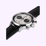 The Hamilton American Classic Intra-Matic Auto Chrono 40 mm Watch H38416711 by Hamilton Watches, featuring a white panda dial, black subdials, date display, and black leather strap, is displayed at an angle on a light purple background.