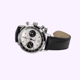 The Hamilton American Classic Intra-Matic Auto Chrono 40mm Watch (H38416711) by Hamilton Watches features a silver chronograph case, white panda dial with two black subdials, H-31 automatic movement, black leather strap, and date display on a lavender background.