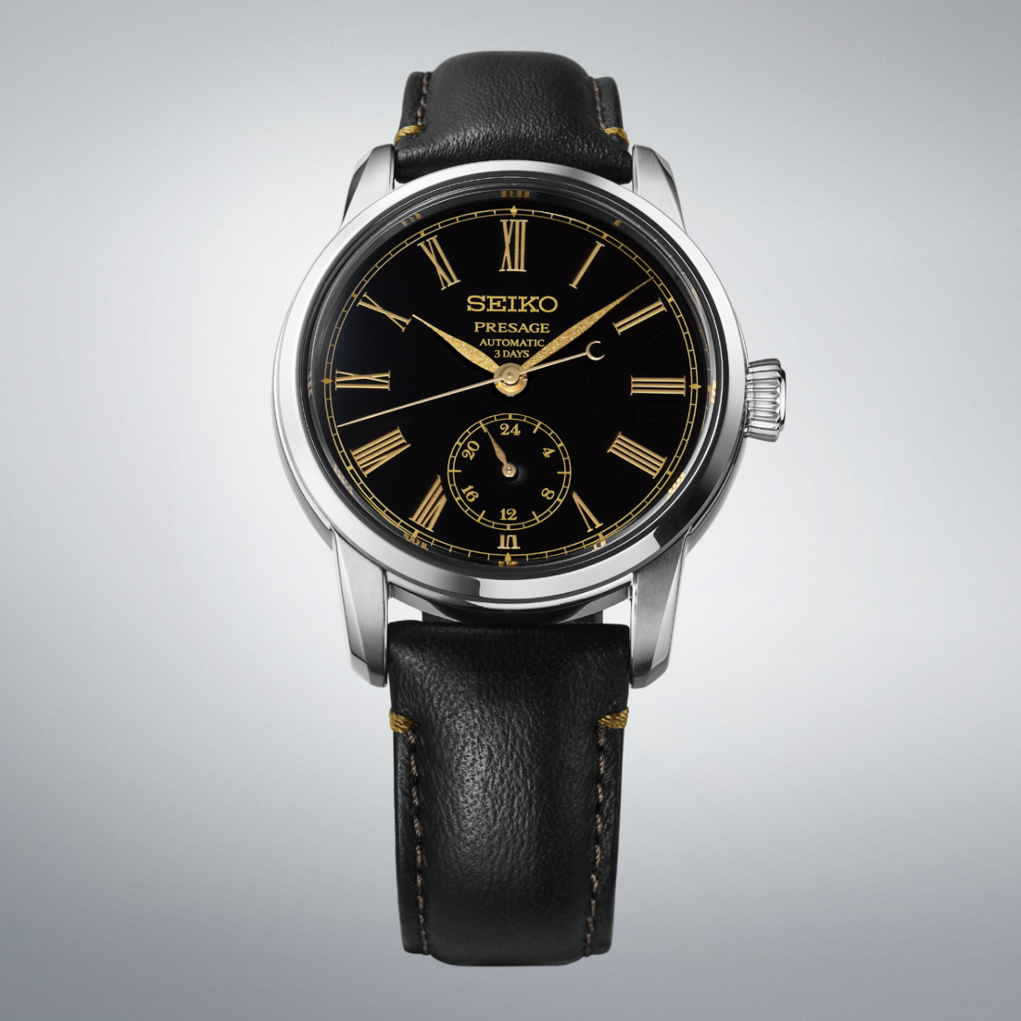 A Seiko Luxe Watches Presage Craftsmanship Series Enamel SPB499 automatic wristwatch featuring a striking black Urushi lacquer dial with gold Roman numerals, a small seconds subdial, and a black leather strap with prominent stitching, displayed against a light gray gradient background.