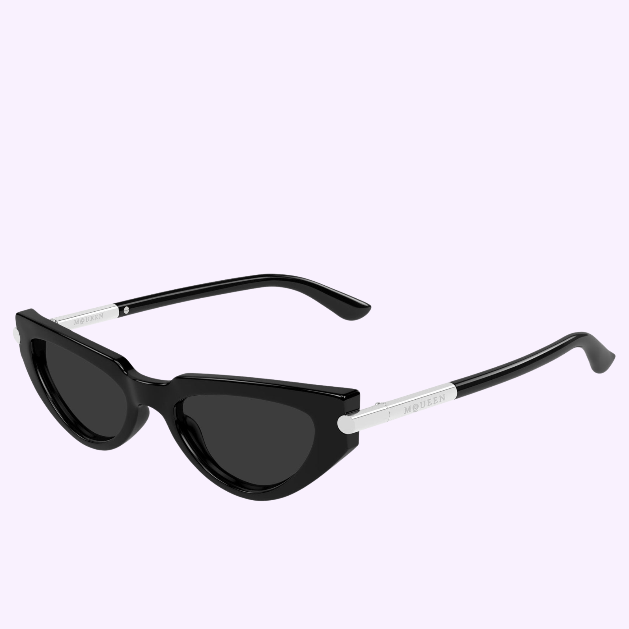 The Alexander Mcqueen Sunglasses AM0520S-001 51 feature bold black cat-eye frames with dark lenses and elegant silver accents on the temples, showcasing the iconic Alexander McQueen branding. Inspired by classic luxury designer eyewear, these sophisticated sunglasses are displayed against a light purple background.