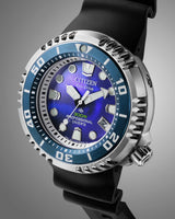 A close-up of the Citizen Watches Promaster Dive E365 BN1025-08L, featuring a blue and silver bezel, blue dial, bold hour markers, and a black rubber strap against a grey gradient background.