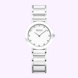 The Bering Watches Ceramic 11429-754 Women's watch features a silver finish, minimalist white round face, silver hour markers, and a ceramic-link bracelet, displayed on a light purple background.