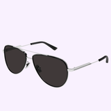 The Bottega Veneta BV1240S-003 59 Sunglass MAN METAL by Bottega Veneta Sunglasses features aviator-style luxury with thin silver frames, black temples, and dark lenses, displayed on a light purple background to highlight the sophistication of handcrafted eyewear.