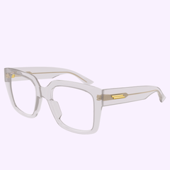 The Bottega Veneta Optical Frames BV1409O-004 51 are transparent, square luxury eyeglasses with thick frames and gold accents on the hinges and arms, shown against a light purple background.