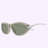 The Bottega Veneta Sunglasses BV1390S-005 56 feature a transparent, cat-eye luxury frame with greenish lenses and metallic knot accents on the temples, displayed against a light purple background. These handcrafted sunglasses by Bottega Veneta capture a refined and elegant aesthetic.