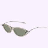 Bottega Veneta Sunglasses BV1390S-005 56—cat-eye sunglasses featuring translucent gray frames, green-tinted lenses, and silver metallic arms reminiscent of luxury eyewear—are displayed against a light purple background.