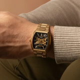 Bulova Watch Maquina 97A207 gold-tone stainless steel men’s watch with an automatic skeletonized movement and black dial worn on a wrist.