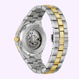 A close-up of the Bulova Watch Prestige Automatic 98A339 by Bulova Watches, featuring a gold and silver-tone stainless steel bracelet, with a transparent case back showcasing its visible automatic movement.