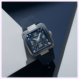 The Bulova Watch Series X Automatic 98A342, a men's timepiece with a square face, blue strap, silver case, and partially skeletonized blue dial, is shown on a blue and white geometric background.