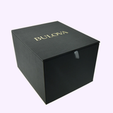 A black, square Bulova Watches box with gold lettering on the lid, closed and set against a plain light background—capturing the refined style of the Bulova Watch Super Seville Magnesite 96A344.