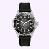 The Bulova Watches Marine Star 98B465 is a silver and black men’s dive watch with a black rubber strap, silver bezel, black dial, luminous markers, date display, and “Automatic” on the face, shown on a light purple background.