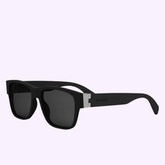 Black rectangular Bvlgari Sunglasses ALUMINIUM BV40022I 5602A with thick frames and dark lenses, displayed at an angle on a light lavender background. A small metallic accent near the hinges on the arms adds an authentic touch, reflecting the signature style of Bvlgari Sunglasses and inspired by the distinctive ALUMINIUM BV40022I collection.