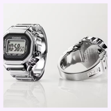 Two silver G-Shock digital wristwatches are displayed; one highlights the digital screen, while the other is angled to reveal the metal strap and back against a neutral background. These classic timepieces showcase G-Shock’s enduring style, in contrast to specialty models like the CASIO RING WATCH CRW001-1.