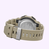 A beige CASIO G-Shock Watch Analog-Digital GA010-5A by G-Shock Watches is featured from the back, showcasing its stainless steel case back, buckle, and a band with rectangular holes against a light purple backdrop. Built with Carbon Core Guard structure for enhanced durability, this model also boasts an impressive 10-year battery life.