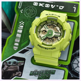 The lime green CASIO G-Shock Watch BA-110 SERIES BA-130YK-3ASW rests on a Mandalorian and Grogu-themed background—ideal for Star Wars fans. The playful G-Shock watch displays the day and time. Brand: G-Shock Watches.