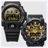 Two G-Shock Watches from the Bold Camo Series—specifically the CASIO G-Shock Watch Bold Camo Series GA700CF-1A—are displayed side by side on a light background, featuring black and gold accents, digital time and date displays, bold rugged designs with camouflage details, and various labeled buttons.