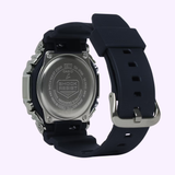 A close-up of the back of a G-Shock Watches G-STEEL GM-2100 Series GM-2100-1ASW with a black strap shows the engraved case back featuring branding, SHOCK RESIST, and water resistance details.