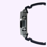Side view of the CASIO G-Shock Watch G-STEEL GM-2100 Series GM-2100-1ASW by G-Shock Watches, featuring a silver case, black strap, and metal buttons against a light purple background.