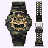 Introducing the CASIO G-Shock Watch Bold Camo Series GA700CMG-3A from G-Shock Watches, a digital and analog timepiece featuring a striking green camouflage pattern, gold accents, and an extra strap displayed on the right.