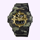 A CASIO G-Shock Watch Bold Camo Series GA700CMG-3A from G-Shock Watches, featuring a green camouflage pattern, rugged design, black and gold face with both digital and analog displays. The digital screen displays the date as SUN 6-30.