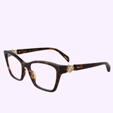 The CHOPARD Optical Frame VCH355 S540909 by Chopard Sunglasses features a rectangular shape with gold accents and arm embellishments, displayed on a light purple background.