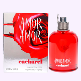 A red bottle of Cacharel Amor Amor 3.4 oz EDT for Women Perfume by Cacharel Perfumes stands beside its matching box, adorned with a bold red rose design and white text displaying the name and brand.