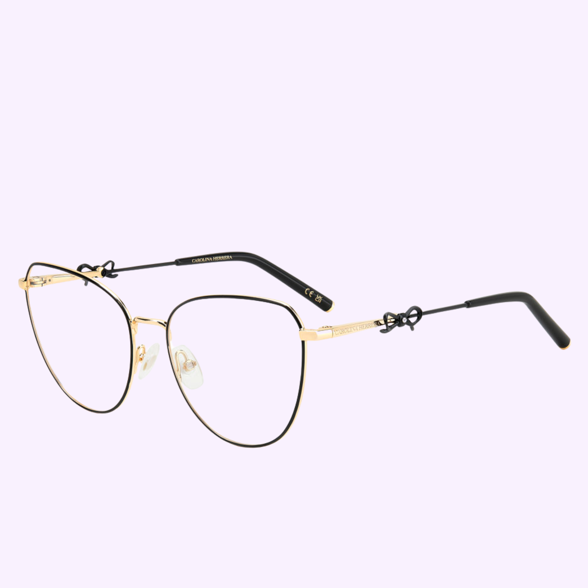 The Carolina Herrera Optical Frames HER 0220 2M2 BLK GOLD features gold and black metal cat-eye frames with clear nose pads and black temple tips, from Carolina Herrera Sunglasses, shown on a light purple background.