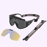 Carrera Sunglasses CARRERA CA Transforma Multi Vision Men ski goggles feature a black frame with a dark lens, an adjustable logo strap, a yellow-tinted replacement lens, and an extra black and red strap—all showcased on a light background. Shop confidently from an Authorized Dealer of Carrera Sunglasses in Miami.