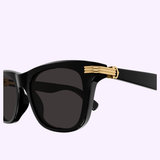 Close-up of Cartier CT0396S-001 53 Men Sunglasses by Cartier Sunglasses, featuring a black rectangular frame with dark lenses and a gold decorative element on the temple, set against a light purple background.