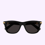 Cartier CT0396S-001 53 men’s sunglasses by Cartier Sunglasses, featuring rectangular black frames with gold accents on the temples, displayed against a light purple background.
