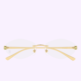 Cartier Optical Frames CT0637O-001 56 by Cartier Sunglasses feature gold-rimmed, rimless eyeglasses with clear oval lenses and decorative green and red gem accents on the temples, evoking true luxury eyewear sophistication against a pale lavender background.