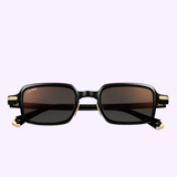 A pair of black Cartier Sunglasses CT0539S 003 with dark lenses and gold hinge accents, featuring the Cartier logo on the left lens, is displayed as luxury eyewear against a light purple background.