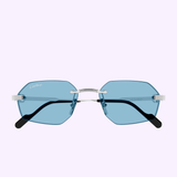 Front view of Cartier Sunglasses CT0616S-005 54, showcasing geometric blue-tinted rimless lenses with silver temples and black tips—luxury Cartier eyewear against a light pastel background.