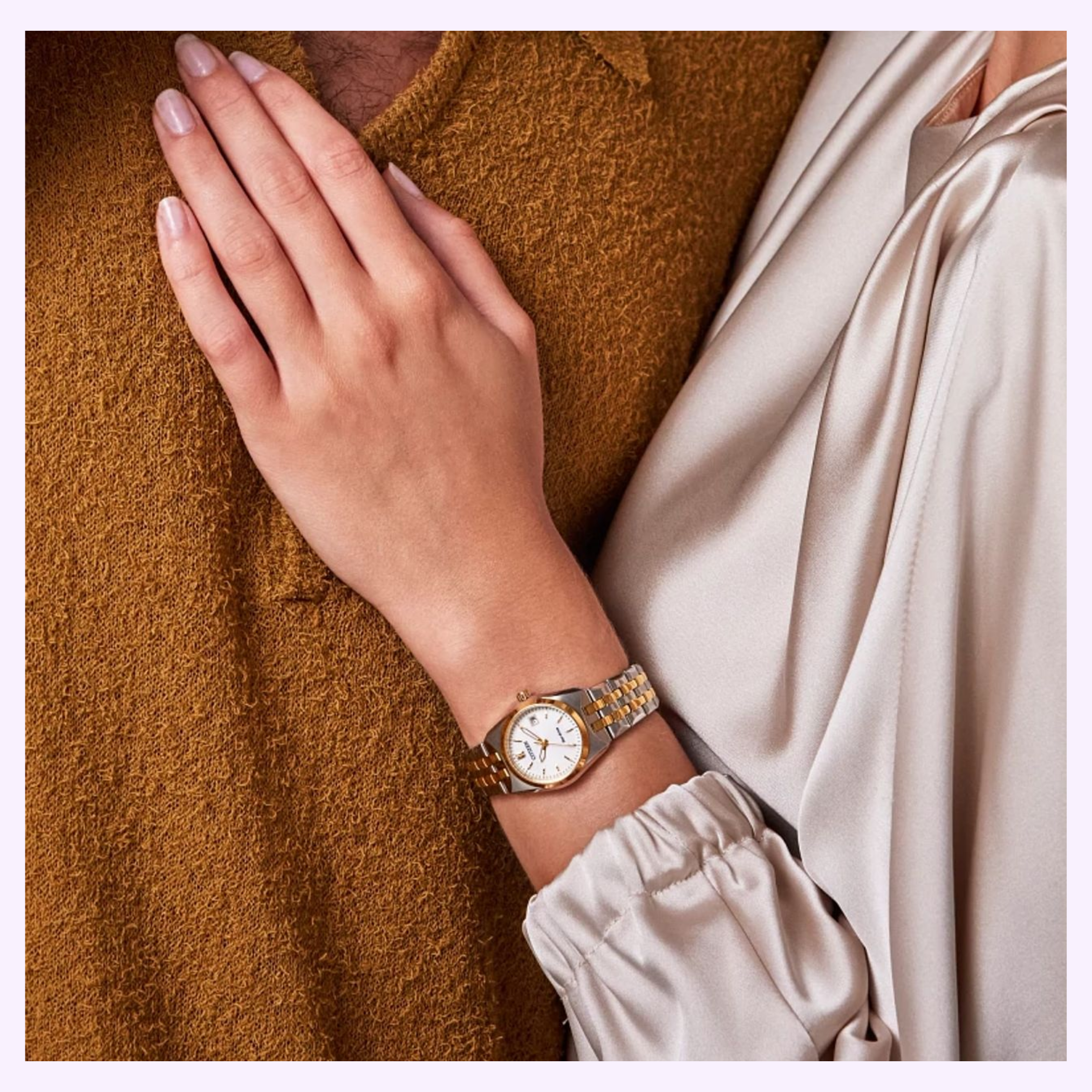 A person in a cream blouse rests their hand—adorned with the Citizen Watches Eco-Drive Corso EW2299-50A, a women’s timepiece with a two-tone stainless steel band—on another individual dressed in a textured brown top.