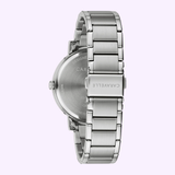 The Bulova 43A155 Caravelle Stainless Steel Strap Men Watch by Caravelle Watches By Bulova is shown from the back, highlighting its brushed metal bracelet and clasp engraved with CARAVELLE against a light purple background.
