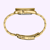 Side view of the Seiko Watches SRPK18 Seiko 5 Sports SGP gold wristwatch with metal band, focusing on crown and clasp, set against a light purple background.