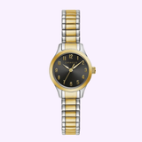 The Bulova 45L185 Traditional Caravelle women’s watch by Caravelle Watches By Bulova features a black face with gold numbers and a two-tone stainless steel band, shown on a light purple background.