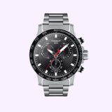 The Tissot T1256171105100 SuperSoft Chronograph by Tissot Watches features a stainless steel strap, black dial with three subdials, tachymeter bezel, silver markers, Swiss movement, and date at 6 o’clock, displayed on a light background.