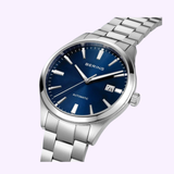 The Bering Watches Classic 19842-707 is a women’s wristwatch with a silver metal band, blue dial, silver hour markers and hands, and a date window at 3 o’clock—showcasing Scandinavian minimalism against a light background.