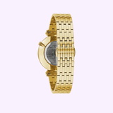 A Bulova Watches 97A153 Regatta gold stainless steel men’s watch is shown from the side, highlighting its metal link strap and partly visible transparent case back, against a light purple backdrop.