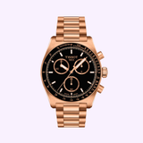 A Tissot Watches PR516 Quartz Chronograph T1494173305100 in rose gold with a black dial, three subdials, and a metal link bracelet is displayed against a light lavender background.