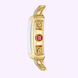 Side view of the Michele Watches MWW06A000780 Deco 18k Gold Diamond Dial Watch, featuring a gold-tone stainless steel case, metallic band, and a red circular emblem with white MW letters, set against a light purple background.