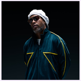 A man wearing the Dita Sunglasses LSA-404 DLS404-56-01RO by Dita Sunglasses, featuring polarized lenses, pairs them with a white beret and a dark green zip-up jacket with yellow stripes—an embodiment of Japanese craftsmanship—as he stands against a dark background.