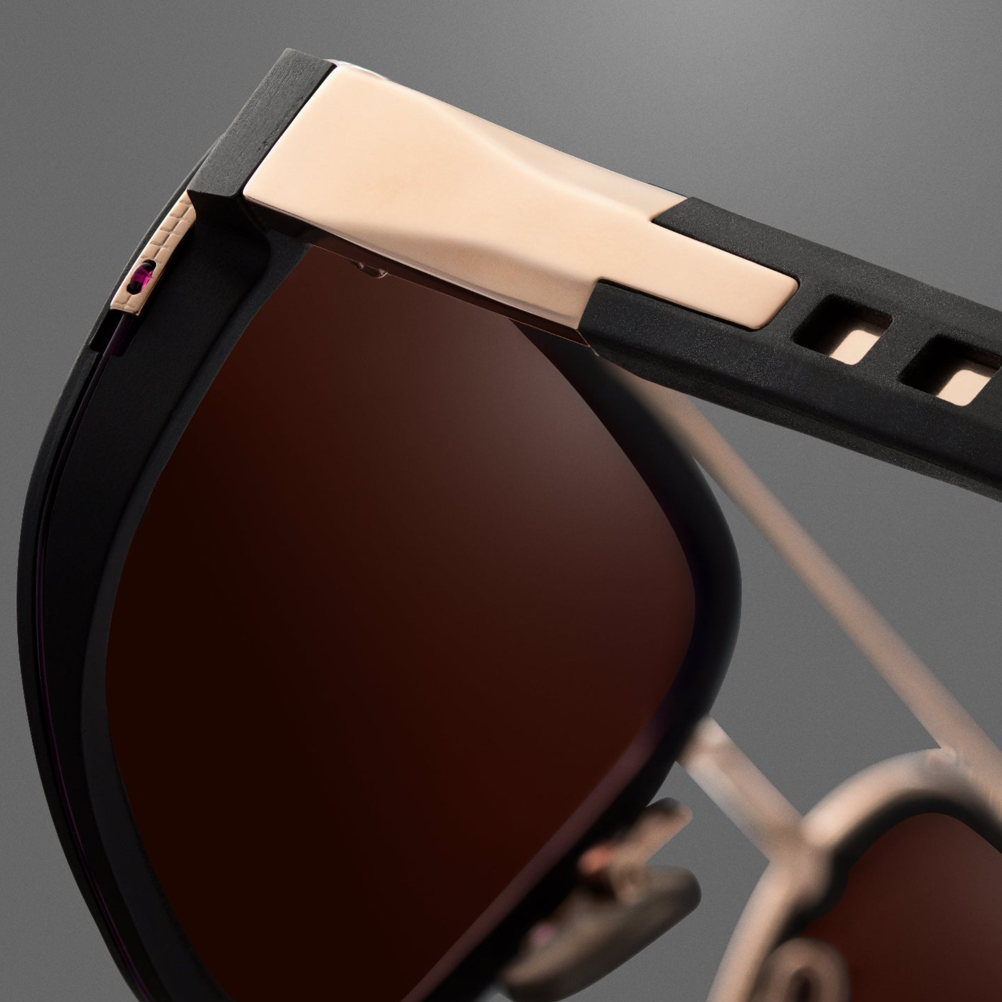 Close-up of the Dita Sunglasses Lancier and Maserati DLS333-A-01 by Dita Sunglasses, featuring a rose gold and black frame, brown tinted lenses, and sleek modern hinge detailing—capturing luxury performance against a gray background.