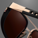 Close-up of the Dita Sunglasses Lancier and Maserati DLS333-A-01 by Dita Sunglasses, featuring a rose gold and black frame, brown tinted lenses, and sleek modern hinge detailing—capturing luxury performance against a gray background.