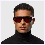 A man in a black turtleneck and Dita Sunglasses RHYTHX DTS741-A-03 Limited Edition with red sculptural navigator lenses looks directly at the camera against a plain light background.